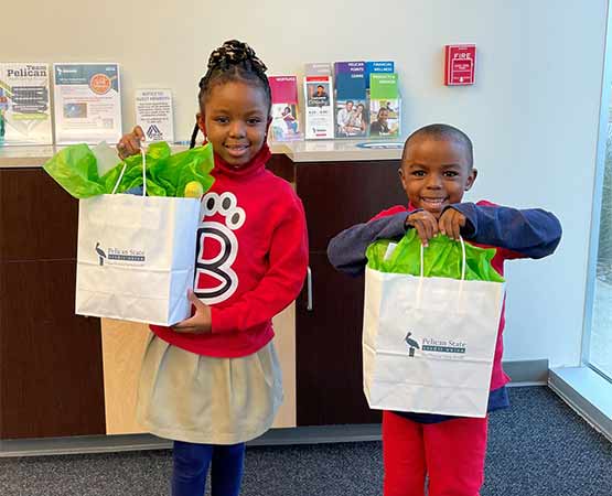 two kids posing with their gift bags